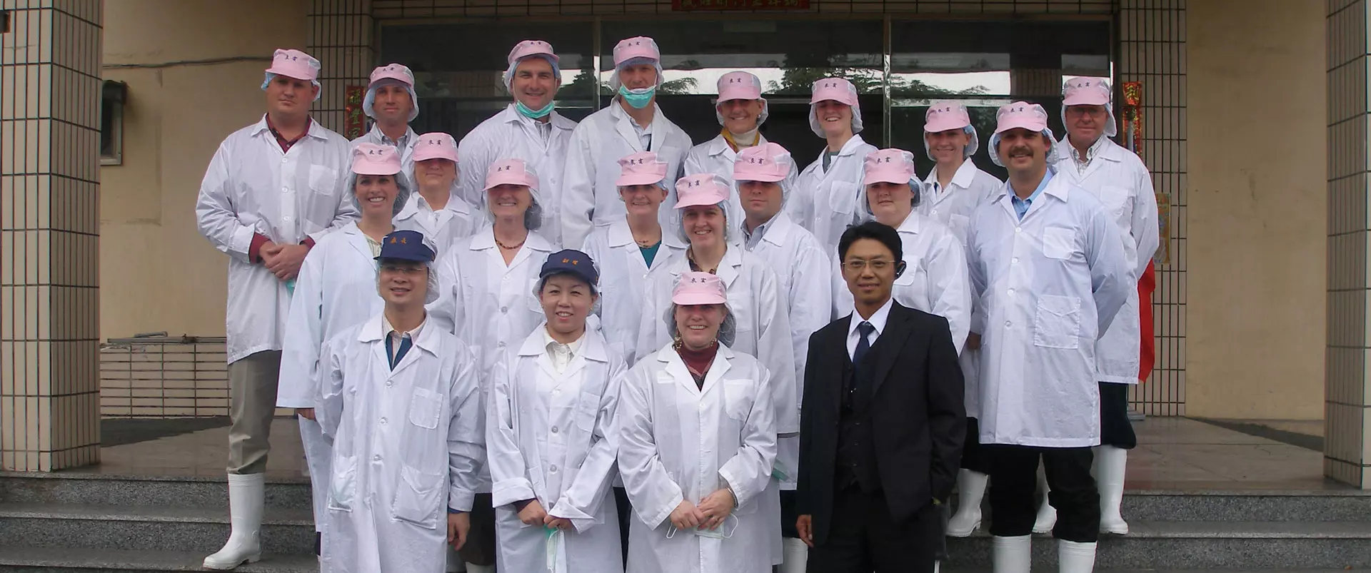 A group of people in white lab coats and pink hats.