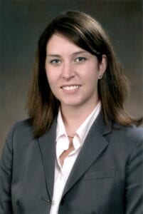 A woman in a suit and tie smiling for the camera.
