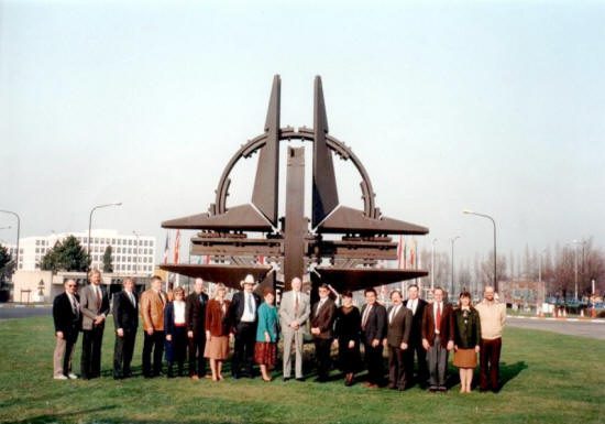 A group of people standing in front of a sculpture.