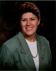 A woman in a green jacket smiling for the camera.
