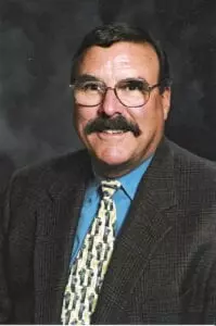 A man with glasses and mustache wearing a suit.