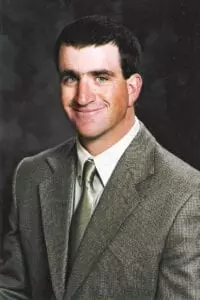 A man in a suit and tie smiling for the camera.