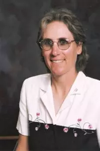A woman wearing glasses and holding a book.