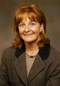 A woman with red hair and a brown jacket.