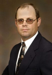 A man in suit and tie wearing glasses.