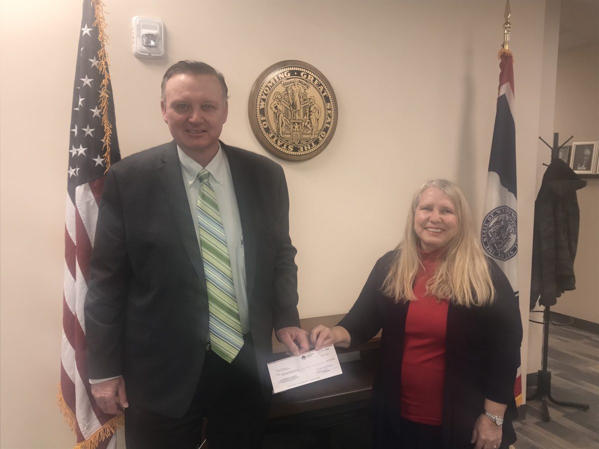 A man and woman holding a box in front of an american flag.